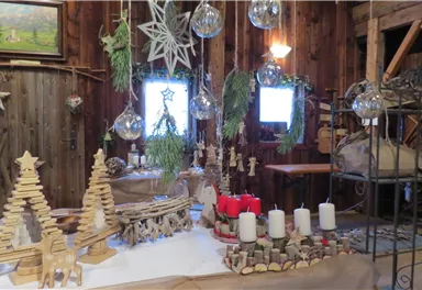 A cozy Christmas decoration with wooden figures and candles. In the background, rustic walls and festive elements can be seen.