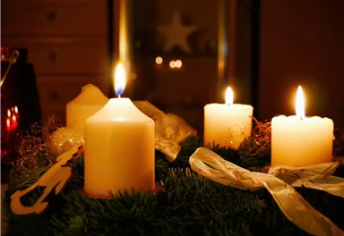 A beautiful Advent wreath with several burning candles. The warm light creates a festive atmosphere.