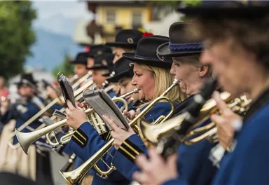 Eine Blaskapelle spielt auf einer Straße. Musiker in blauen Uniformen halten ihre Instrumente und konzentrieren sich auf die Musik.