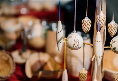 Colorful wooden symbols are hanging from a string. In the background, more wooden objects are visible.