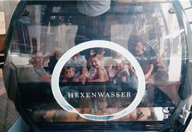 A gondola with various people happily waving. In the window it says "WITCH WATER".