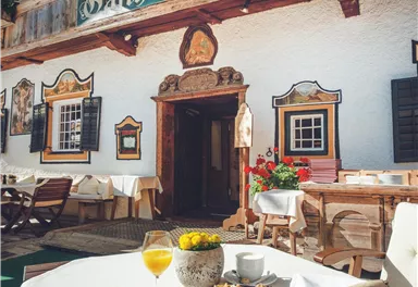 An inviting inn with a beautiful outdoor area and blooming flowers. Breakfast plates and drinks are ready on the table.