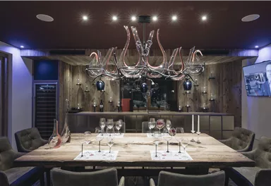 An elegant dining area with a large wooden table and stylish chairs. Above the table hangs a striking lamp, accompanied by decorative elements.