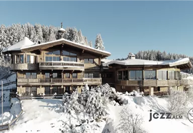 Ein wunderschönes Chalet inmitten einer schneebedeckten Landschaft. Umgeben von verschneiten Bäumen und Bergen bietet es eine gemütliche Atmosphäre.