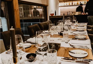 Ein elegant gedeckter Tisch in einem gemütlichen Restaurant. Die Atmosphäre ist warm und einladend, mit Holzdekor und schöner Tischdekoration.