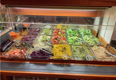 Ein Salatbuffet mit verschiedenen bunten Gemüsesorten und Dressings. Es bietet eine Vielzahl von gesunden Optionen in klaren Behältern.