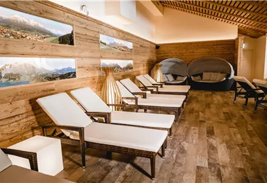 Ein ruhiger Wellnessbereich mit bequemen Liegen und gemütlichen Ruhezonen. Die Wände sind aus Holz und mit schönen Landschaftsbildern dekoriert.