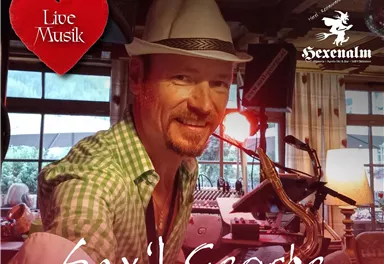 Ein Musiker spielt Saxophon in einem gemütlichen Ambiente. Die Veranstaltung steht unter dem Motto "Live Musik".