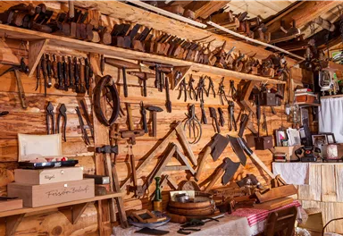 A workshop with a wall full of woodworking tools and utensils. The room is cozy and rustic.