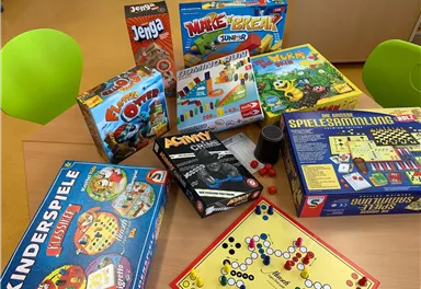 Eine Auswahl von Brettspielen liegt auf einem Tisch. Die Spiele sind bunt und reichen von klassischen bis zu modernen Kinderspielen.