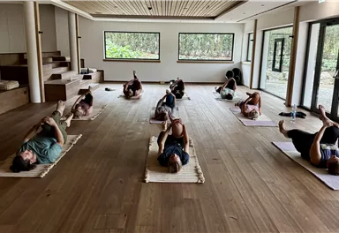 A quiet yoga room with several people lying on mats. The gentle lighting creates a relaxing atmosphere.