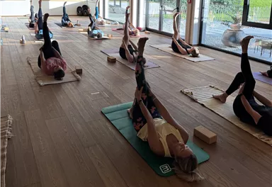 A calming yoga class in a cozy wooden room. Participants practice in a relaxed atmosphere with dim lighting.