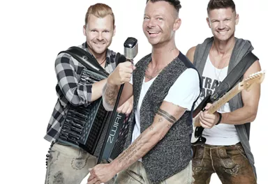 Drei Musiker posieren fröhlich vor einem weißen Hintergrund. Sie halten verschiedene Musikinstrumente und tragen legere Kleidung.