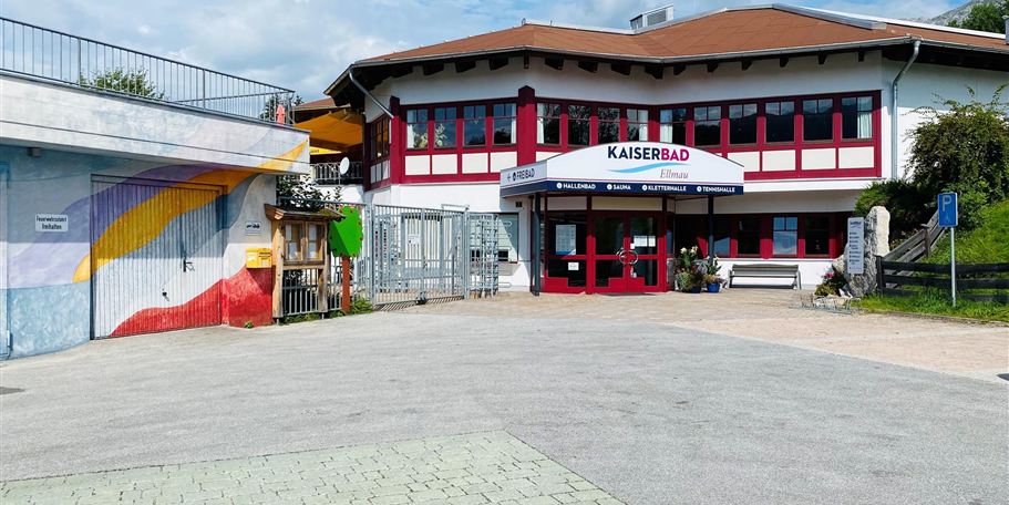 A modern building with the inscription "Kaiserbad". There are colorful murals and an inviting entrance door.