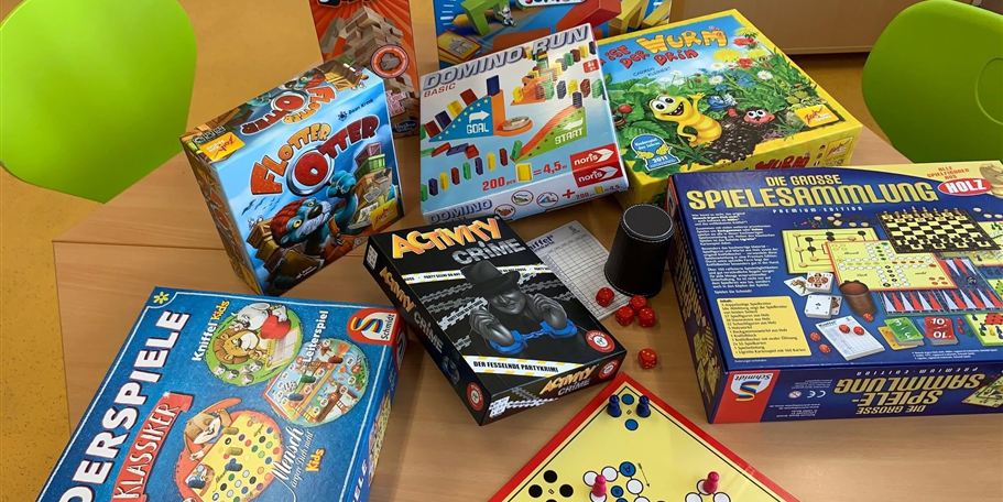 A selection of board games is spread out on a table. The games are colorful and range from classic to modern children's games.