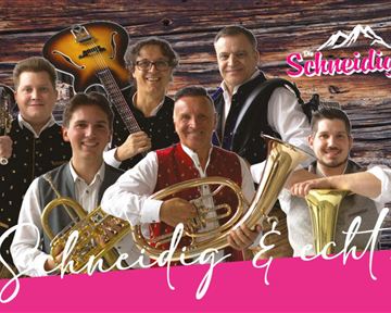 A group of six musicians stands in front of a wooden wall. They are wearing traditional costumes and holding various musical instruments.