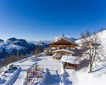Ein malerisches Bergdorf im Schnee mit einer gemütlichen Hütte. Der Himmel ist klar und blau, umgeben von schneebedeckten Hügeln.