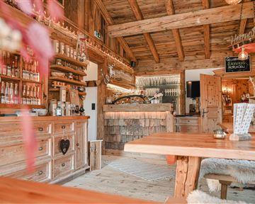Ein gemütlicher Innenraum mit Holzdekor, Theke und mehreren Tischen. Die Atmosphäre ist warm und einladend.