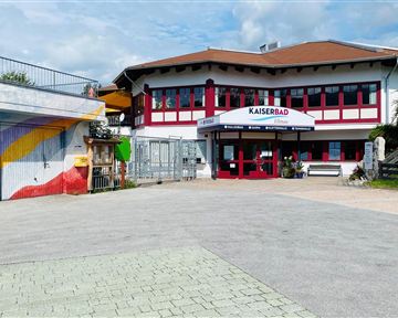 Ein modernes Gebäude mit dem Schriftzug "Kaiserbad". Es gibt bunte Wandmalereien und eine einladende Eingangstür.