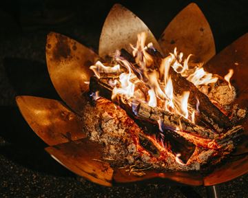 Ein schönes Feuer in einem dekorativen Feuerkorb. Die Flammen tanzen über das brennende Holz.