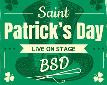 A group of cheerful skiers stands together holding various flags. They are wearing winter sports clothing and smiling at the camera.