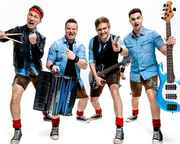 Eine fröhliche Band mit fünf Mitgliedern posiert in einer Action-Haltung. Sie tragen Trachtenlooks und halten verschiedene Musikinstrumente in der Hand.