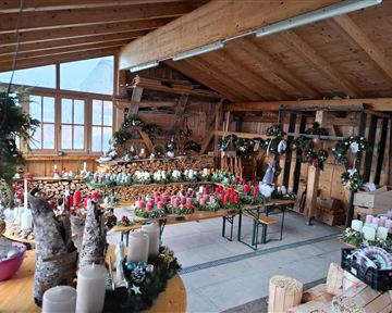 Ein gemütlicher Raum mit Holzdekor, geschmückt für die Weihnachtszeit. Auf Tischen stehen viele Kerzen und festliche Dekorationen.