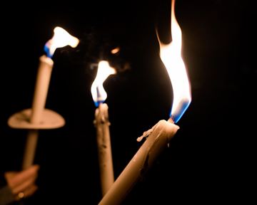 Three burning candles in the dark. The light of the flames creates a cozy atmosphere.