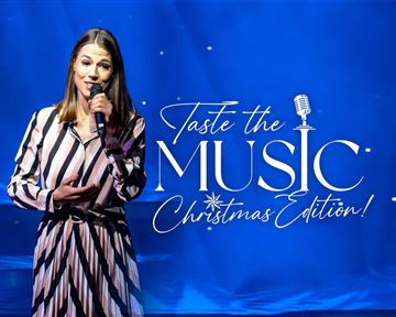 Eine Frau steht auf der Bühne und singt in ein Mikrofon. Im Hintergrund ist eine festliche Weihnachtsdekoration zu sehen.