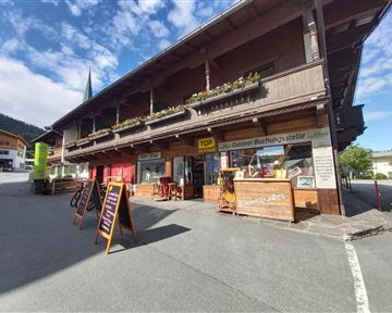 A beautiful wooden building with blooming flower boxes. Outside, there are signs for an outdoor booking spot.