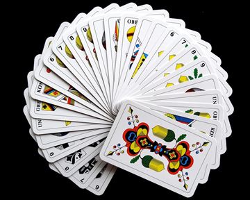 Ein fächerartiges Arrangement von Spielkarten auf schwarzem Hintergrund. Die Karten zeigen verschiedene bunte Designs und Zahlen.