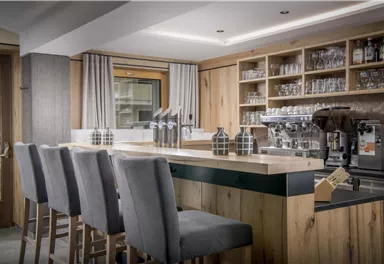 Eine moderne Bar mit Holzregalen und eleganten Stühlen. Die Atmosphäre ist einladend und gemütlich.