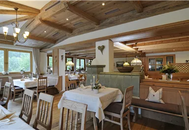 Ein gemütliches Restaurant mit Holzmöbeln und warmem Licht. Tische sind schön gedeckt und bieten eine einladende Atmosphäre.