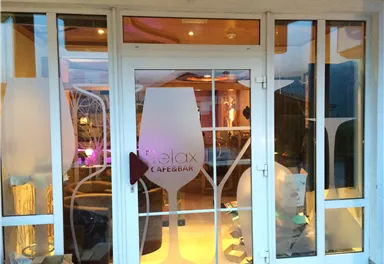 A modern café with large window fronts. The decor is stylish and invitingly lit.