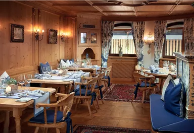 A cozy restaurant with wooden walls and blue cushions. The tables are elegantly set, creating an inviting atmosphere.