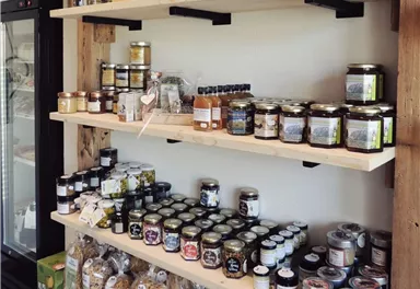 A shelf with various food items, including jars of jam, sauces, and oils. The products are beautifully arranged and look inviting.