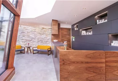 Ein modernes Empfangsbereich mit Holzmöbeln und einem hellen, einladenden Ambiente. Die Wände sind mit eleganten Steinverkleidungen dekoriert.