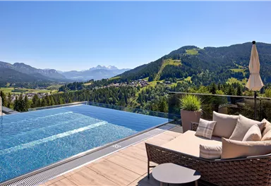 A luxurious infinity pool with views of the mountains and the surrounding nature. A cozy seating area and sunshade provide relaxation and comfort.