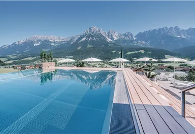 Ein atemberaubender Infinity-Pool mit Blick auf die beeindruckenden Berge. Klare Himmel und Sonnenschirme schaffen eine entspannende Atmosphäre.