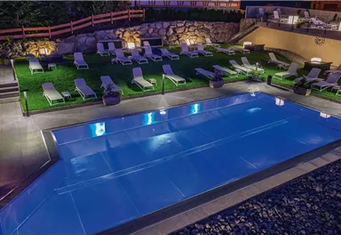Ein moderner Pool mit klar blauem Wasser und gemütlichen Liegen. Der Gartenbereich ist gut beleuchtet und hat eine einladende Atmosphäre.