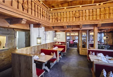 A cozy restaurant with wooden interiors and red benches. The warm atmosphere is enhanced by the wooden ceiling and soft lighting.