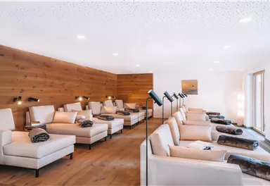 Ein ruhiger Entspannungsraum mit bequemen Liegen. Die Wände sind aus Holz und der Raum ist gut beleuchtet.