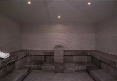 Ein modernes Dampfbad mit grauen Wänden und Sitzbänken. Es ist schlicht und einladend, ideal zum Entspannen.