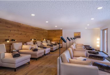 Ein ruhiger Entspannungsraum mit bequemen Liegen und sanfter Beleuchtung. Die Holzwände sorgen für eine gemütliche Atmosphäre.