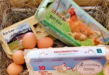 Fresh organic eggs from free-range farming in a wooden box. Visible are eggs, a hen on the packaging, and a label with information.