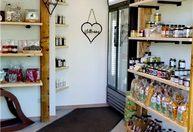 An inviting shop with shelves full of jams, oils, and other foods. The entrance area is bright and friendly designed.