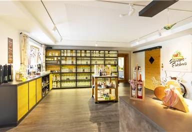 Ein einladender Verkaufsraum mit Regalen voller Flaschen und Produkten. Es gibt eine Theke und einen charmanten Dekorationsbereich.