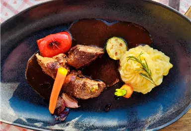 A delicious plate with tender meat, served with an aromatic sauce. Accompanied by mashed potatoes and fresh vegetables.