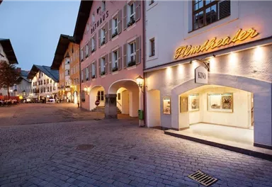 Ein malerischer Platz mit historischen Gebäuden und einem Kino. Die Abendstimmung sorgt für eine einladende Atmosphäre.
