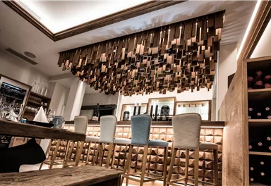 Eine elegante Bar mit einem modernen Holzdekor und stilvollen Barhockern. Die Atmosphäre ist freundlich und einladend.